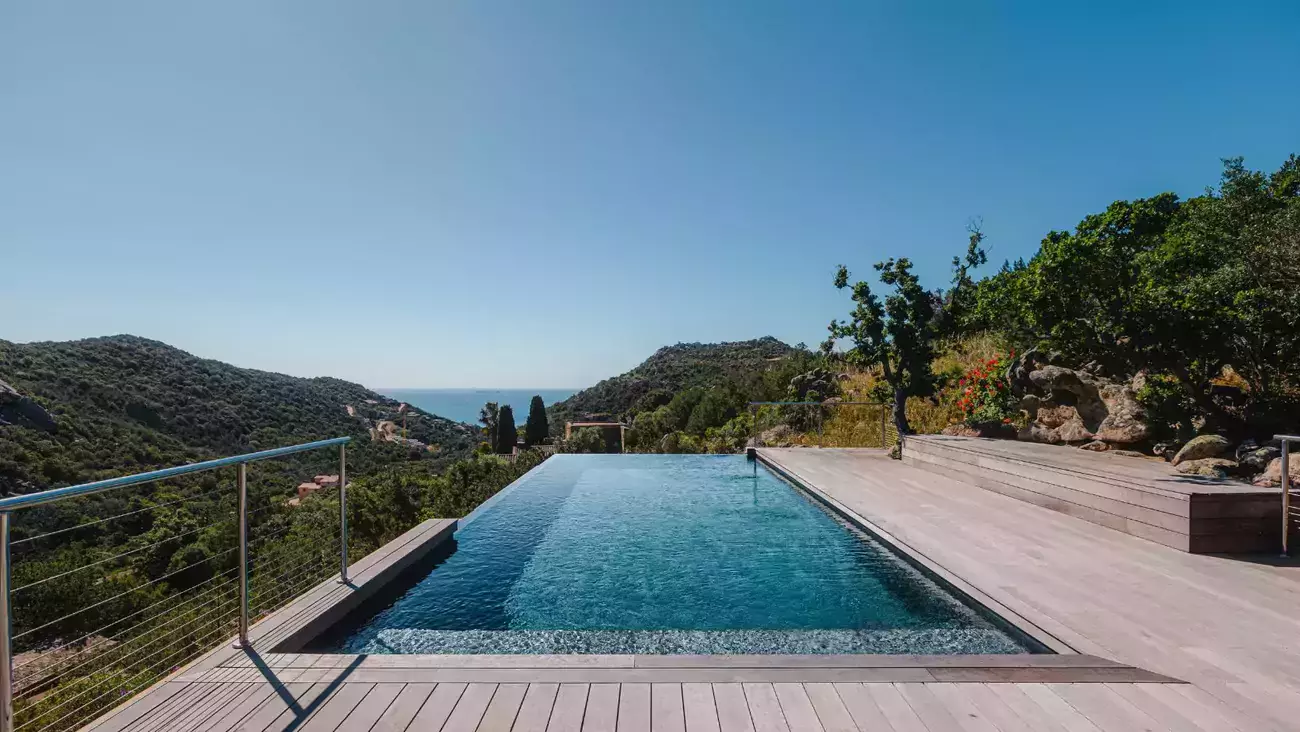 Dans le décor sauvage de la Corse, une piscine à débordement est le point central d'un jardin, alliant vue magnifique et tranquillité.