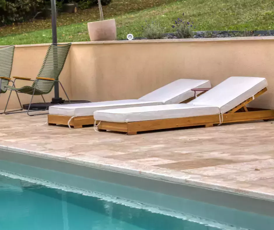 Une piscine baignée d'un ton olive, jumelée à une terrasse en travertin.