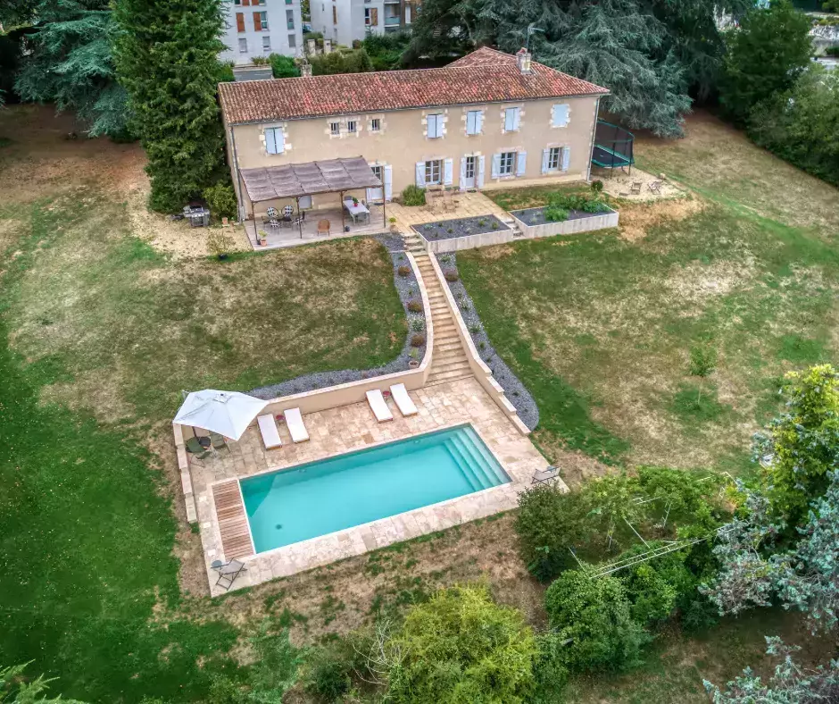 Une piscine teintée d'une subtile teinte d'olive, accompagnée d'une terrasse en travertin.