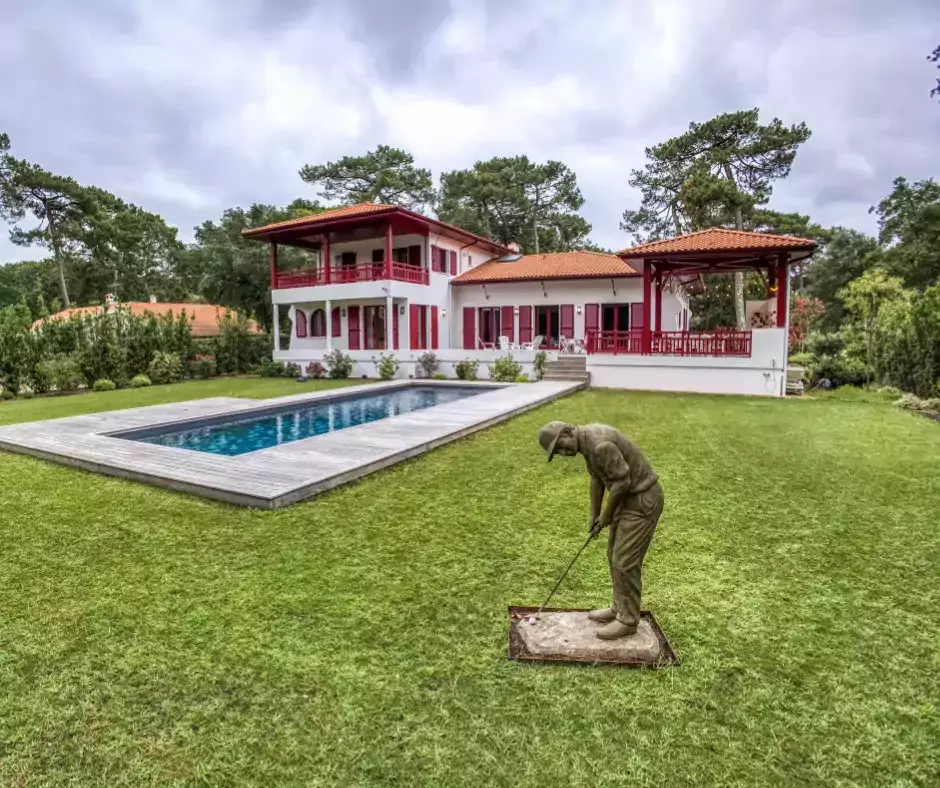 Piscine revêtue de pierre de Bali accompagnée d'une terrasse bois, évoquant l'élégance Basque.