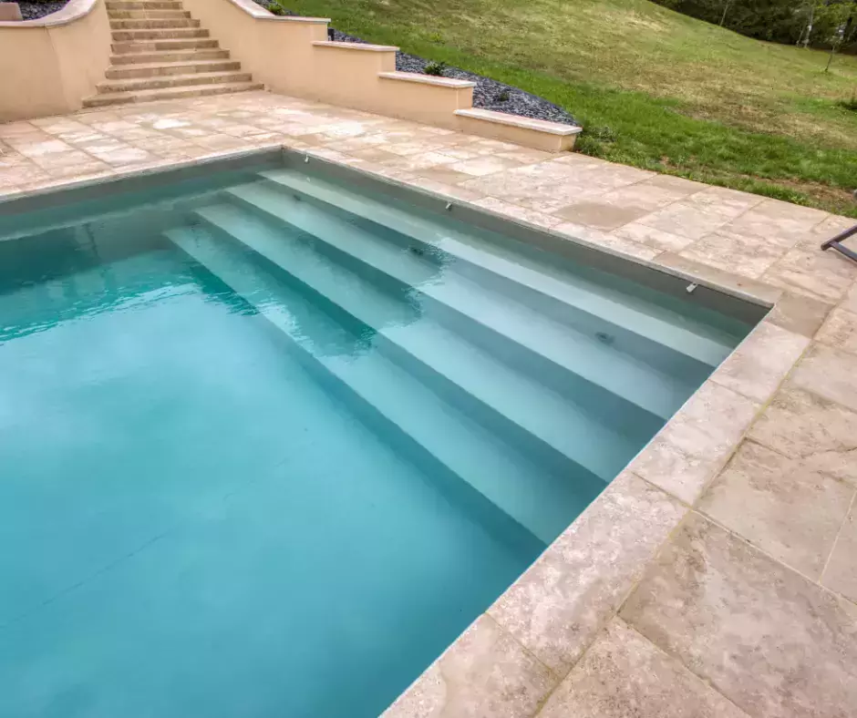 Une piscine à la couleur d'olive et une terrasse revêtue de travertin.