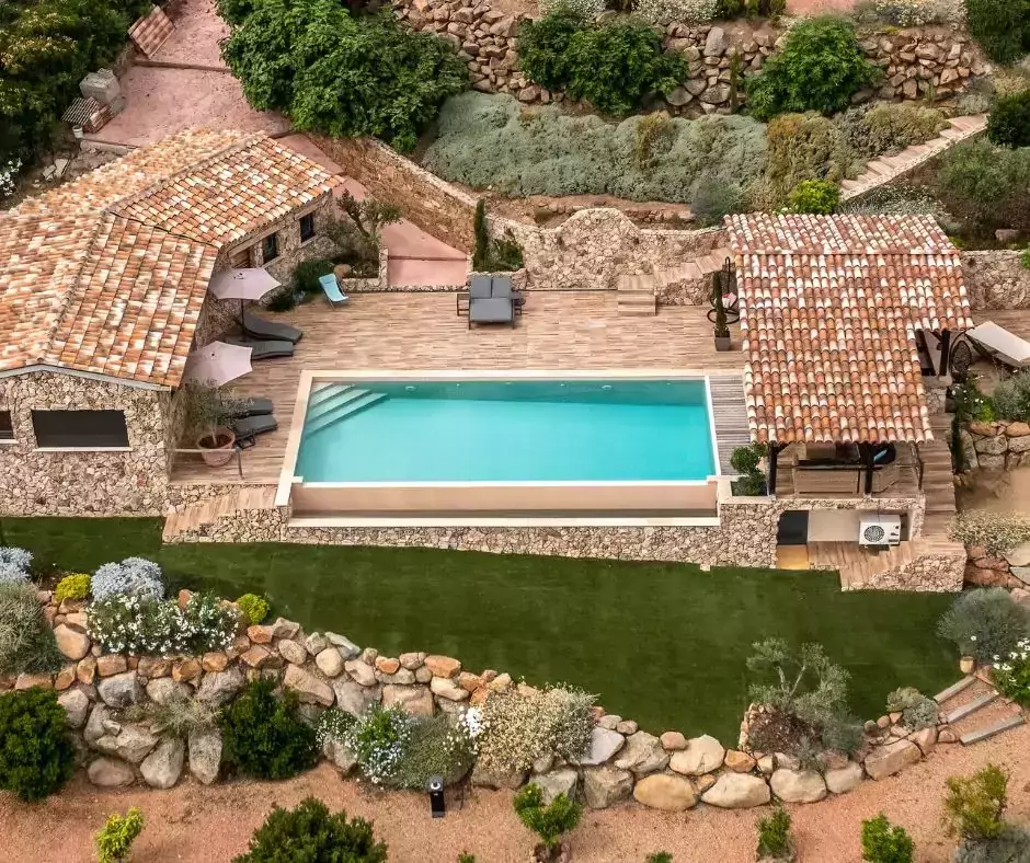 Jardin d'une maison en pierre avec piscine à débordement avec pool house