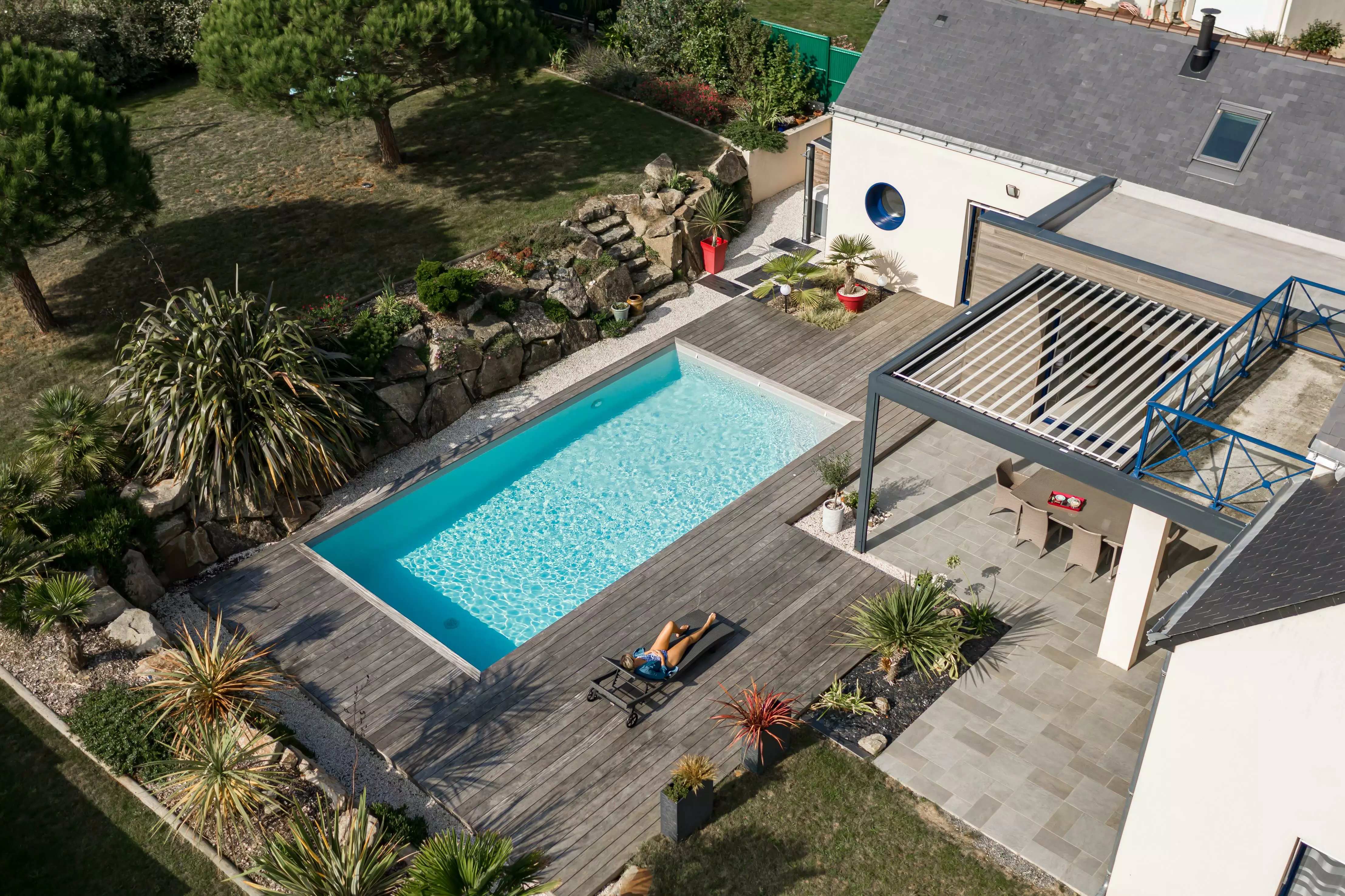Une construction contemporaine où la piscine est l'élément central, entourée d'une terrasse qui mène à un paysage rocheux parsemé de plantes exotiques.