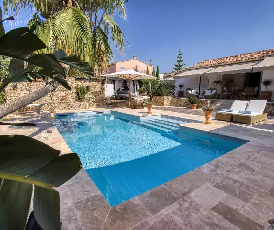 Perfectionnement d'une piscine coque en une version maçonnée moderne, avec un palmier emblématique, une cascade dynamique et un sol en travertin.
